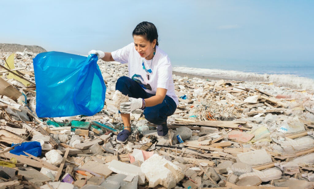 woman picks up trash on the beach