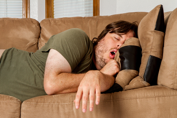 Man taking a quick nap on the couch with his mouth open