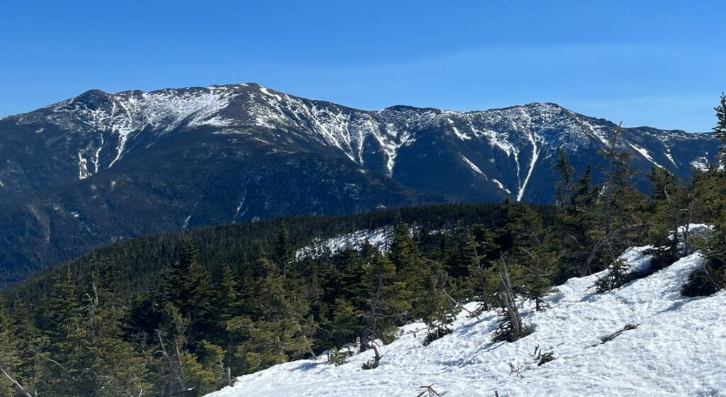 A photo taken on the slopes at Cannon Mountain in New Hampshire, with snow covered mountains in the distance.