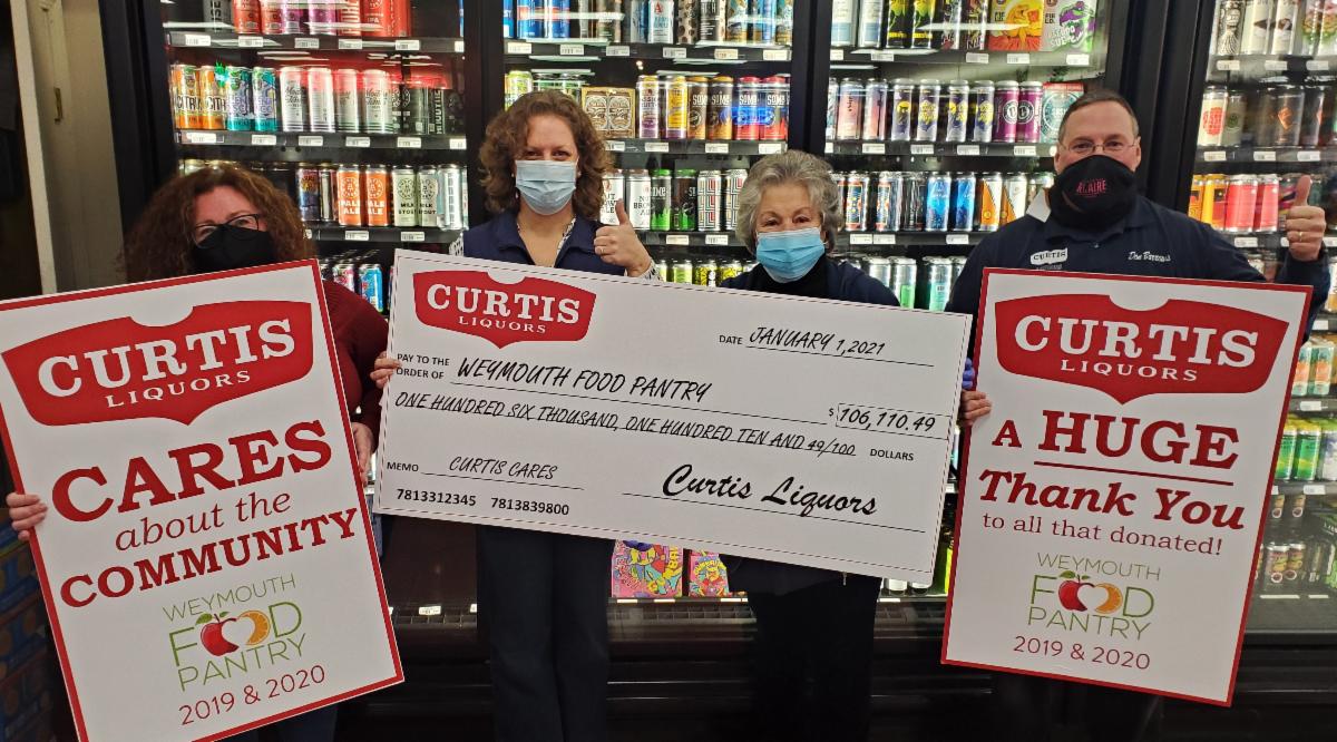 four people holding checks from curtis liquors to weymouth food pantry