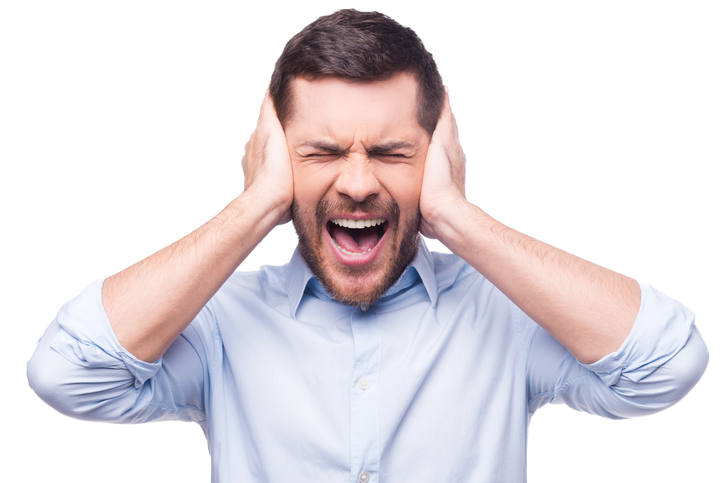 Frustrated young man in formalwear holding head in hands and keeping eyes closed while standing against white background