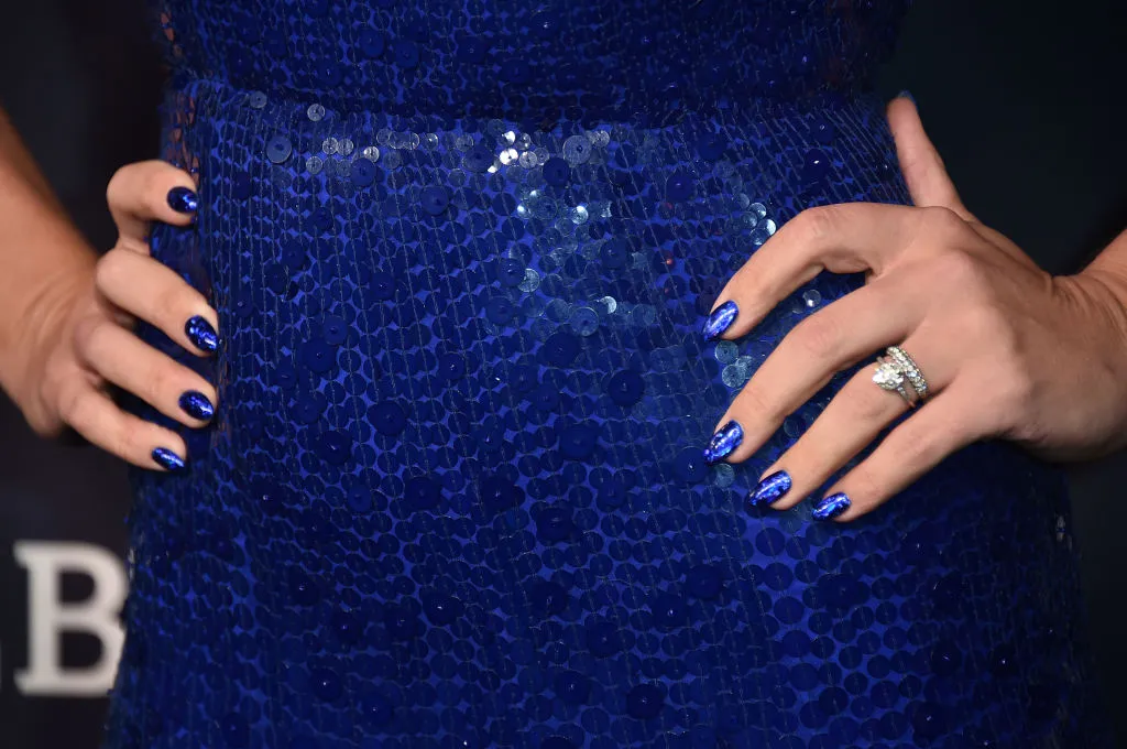 woman with hands on her hips in a blue dress with blue nail polish