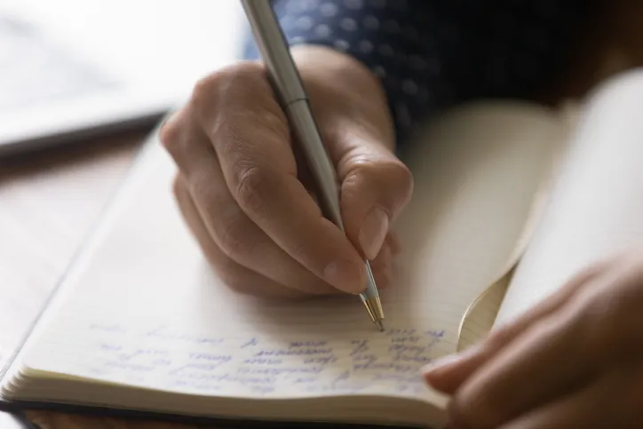 Hands of woman taking notes in a notebook